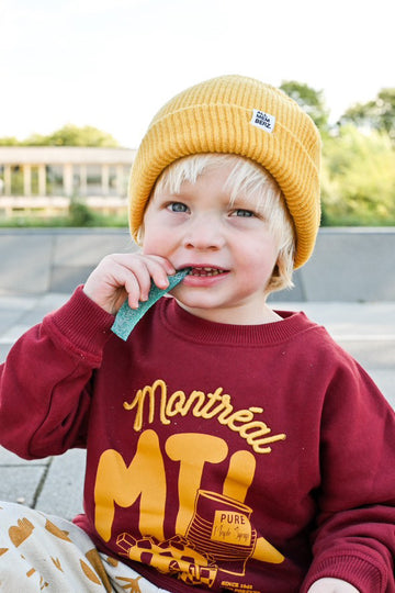 petit garçon dans un skatepark look streetwear cool unisexe sweat bordeaux oversize en coton bio motif Montreal illustration jaune moutarde, bonnet en laine pour enfant