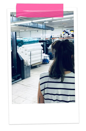 une styliste visite une usine de confection de vêtements pour enfants au Portugal, machines industrielles et rouleaux de tissu