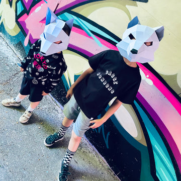 deux enfants en tenue streetwear portant des masques en papier, fond graffiti coloré