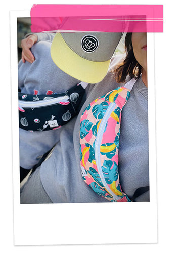 un garçon portant une casquette cool pour enfant à visière plate jaune, un sweat gris et un sac banane imprimé, avec sa maman look matchy maman enfant