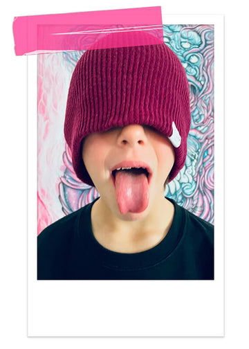 un garçon tirant la langue, portant un bonnet cool pour enfant style snowboardeur