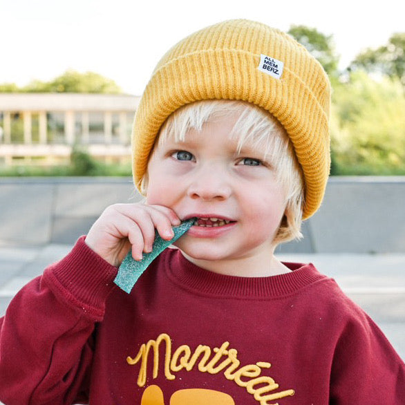 petit garçon dans un skatepark look streetwear cool unisexe sweat bordeaux oversize en coton bio motif Montreal illustration jaune moutarde, bonnet en laine pour enfant