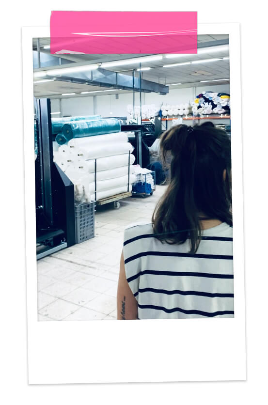 une styliste visite une usine de confection de vêtements pour enfants au Portugal, machines industrielles et rouleaux de tissu