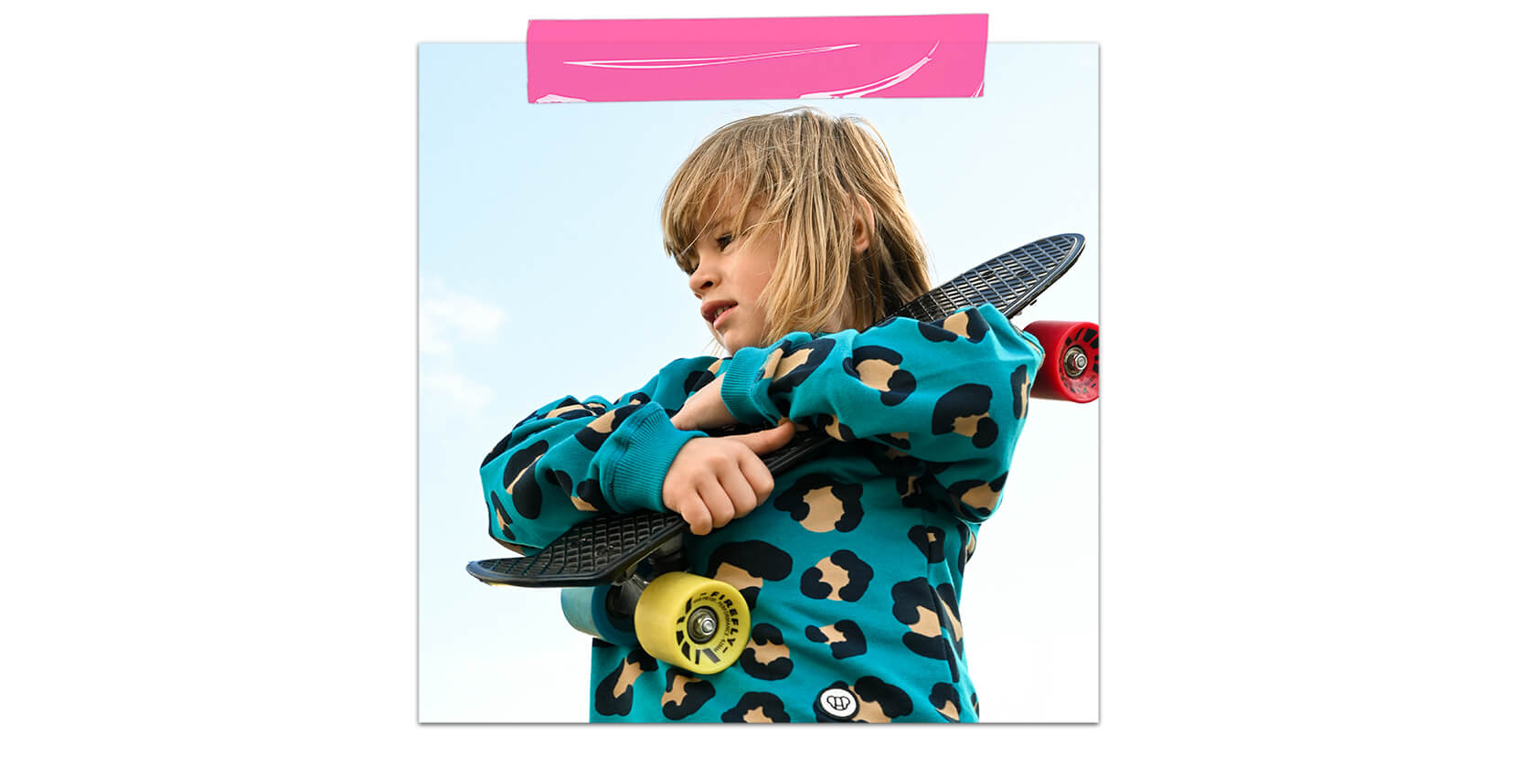 garçon de 8 ans tenant skateboard, portant un sweat léopard pour enfant, couleurs vives et flashy