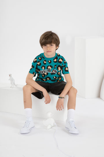 Garçon de 8 ans portant un t-shirt streetwear cool pour enfant, coupe oversize unisexe en coton biologique, motif imprimé léopard fond vert bleu, short large jean noir, baskets montantes blanches, dans un décor monochrome blanc