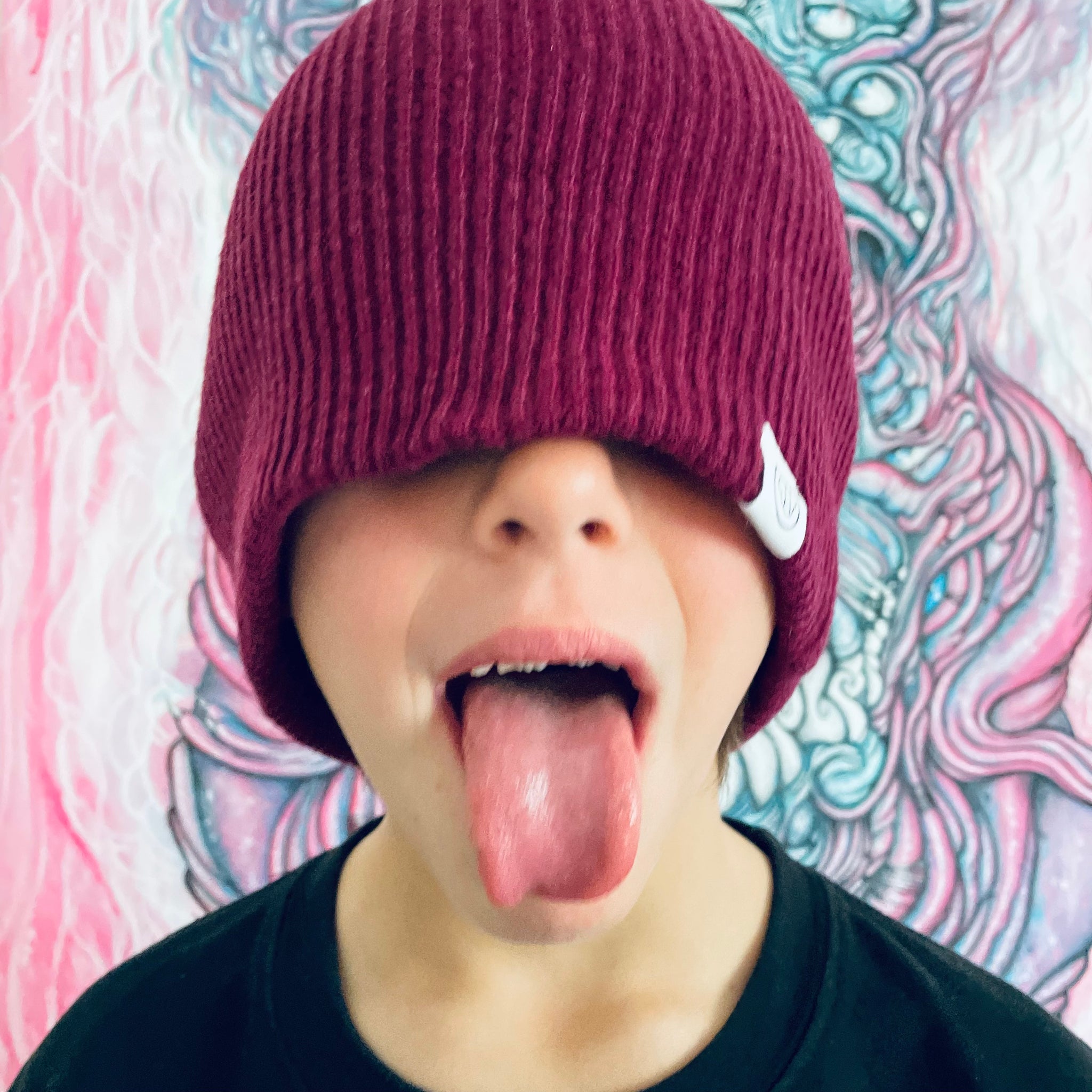enfant espiègle portant un bonnet cool en laine et tirant la langue