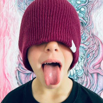 enfant espiègle portant un bonnet cool en laine et tirant la langue