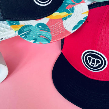 casquette snapback réglable pour enfant style cool, visière plate, en coton et maille filet, rouge cerise et noir, logo ours Allmemberz brodé devant, casquette visière imprimée tropical